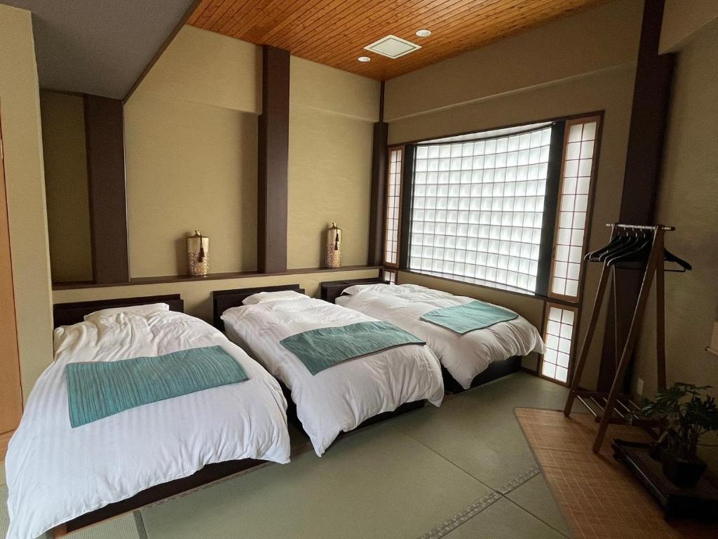 2 Betten in einem Zimmer mit 2 Fenstern in der Unterkunft 雅 in Nishinotōindōri
