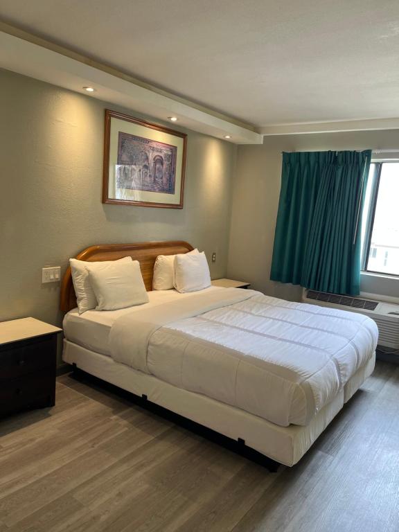 1 dormitorio con 1 cama blanca grande y ventana en 777 Motor Inn, en Huntington Beach