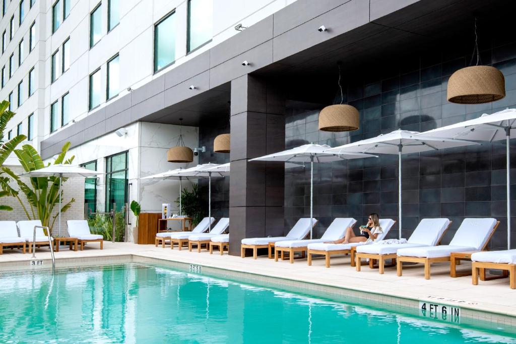 a woman sitting on a chair next to a swimming pool at ette luxury hotel & spa in Orlando