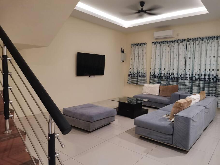 a living room with two couches and a flat screen tv at Cozzy26 Homestay in Bintulu