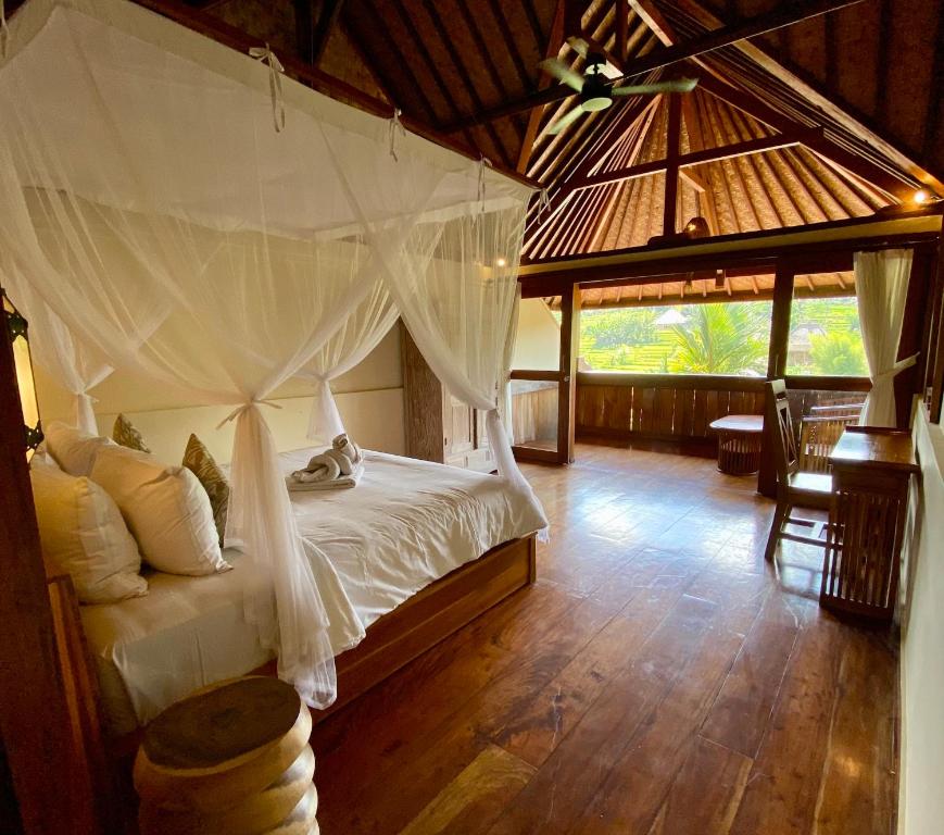 a bedroom with a bed with a mosquito net at Abian Ayu Villa in Sidemen