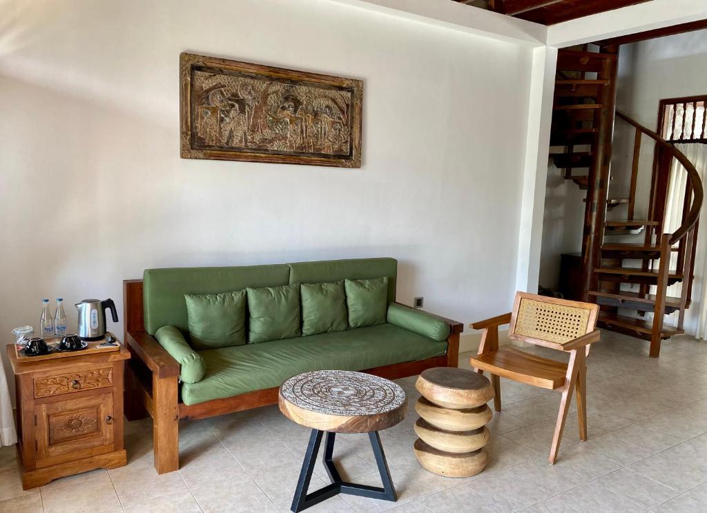 a living room with a green couch and wooden furniture at Abian Ayu Villa in Sidemen