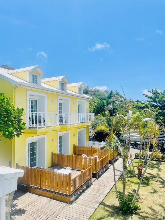 una grande casa gialla con terrazza in legno di Canaan B&B Kenting a Eluan