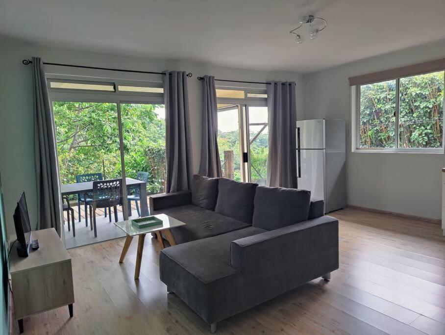uma sala de estar com um sofá e uma mesa em Logement cozy avec Jardin em Arue