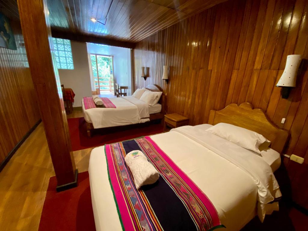 two beds in a room with wooden walls at Mistico Machupicchu Eco B&B in Machu Picchu
