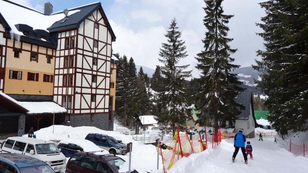 a person on skis in the snow next to a building at Apartmán Javor in Pec pod Sněžkou