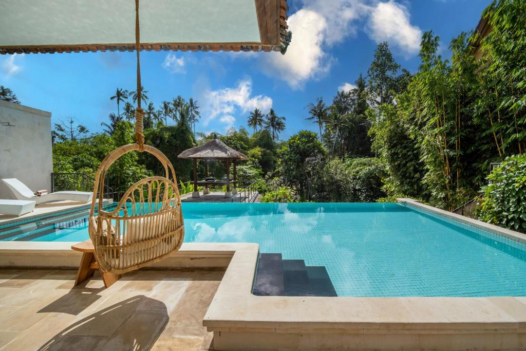 a pool with a swing and a chair next to a house at Luxury Villa in City Center w/ Natural Pool La Bohemia Residence Villas in Ubud