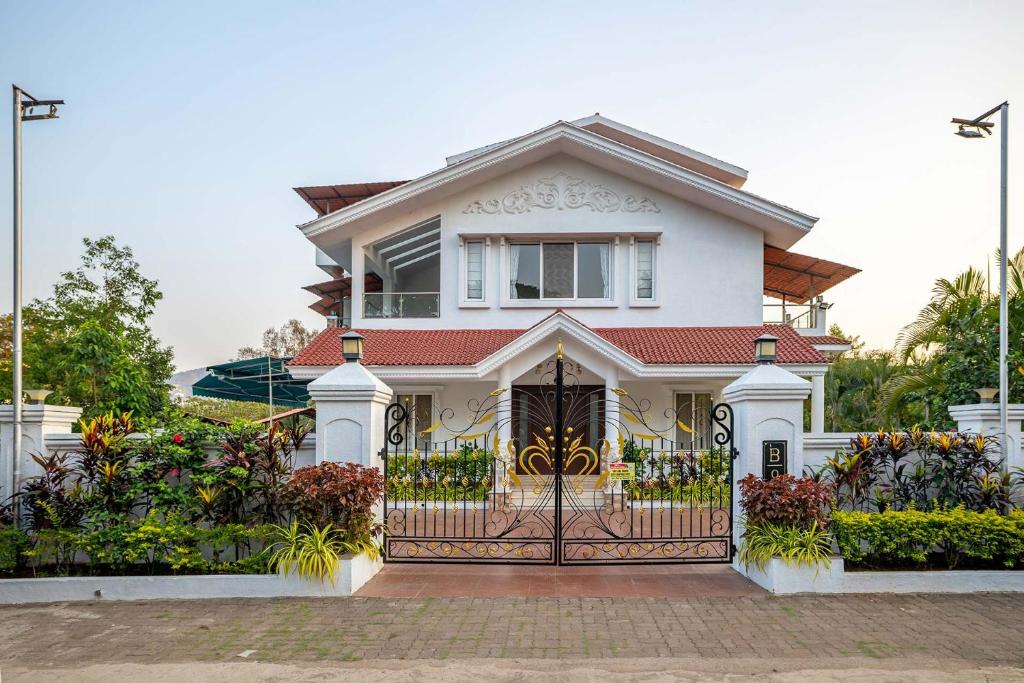 a white house with a gate in front of it at Casa Serenity by StayVista - Relax with a pool, lawn, and inviting jacuzzi in Lonavala