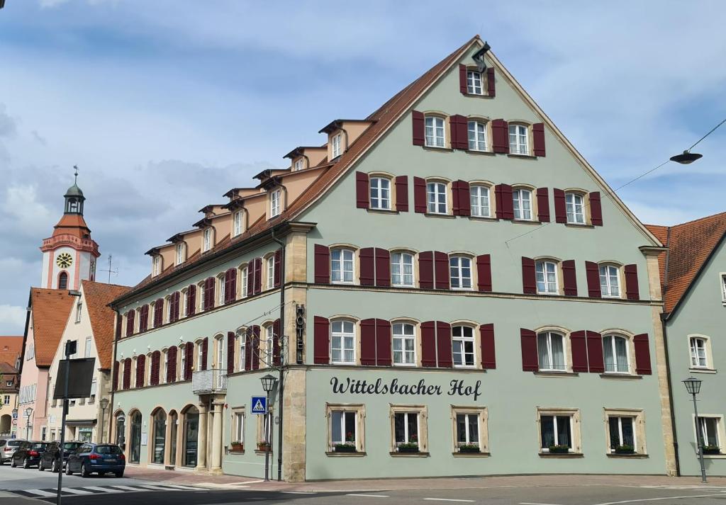 un grand bâtiment blanc avec des fenêtres rouges et une tour d'horloge dans l'établissement Wittelsbacher Hof Weißenburg, à Weißenburg in Bayern