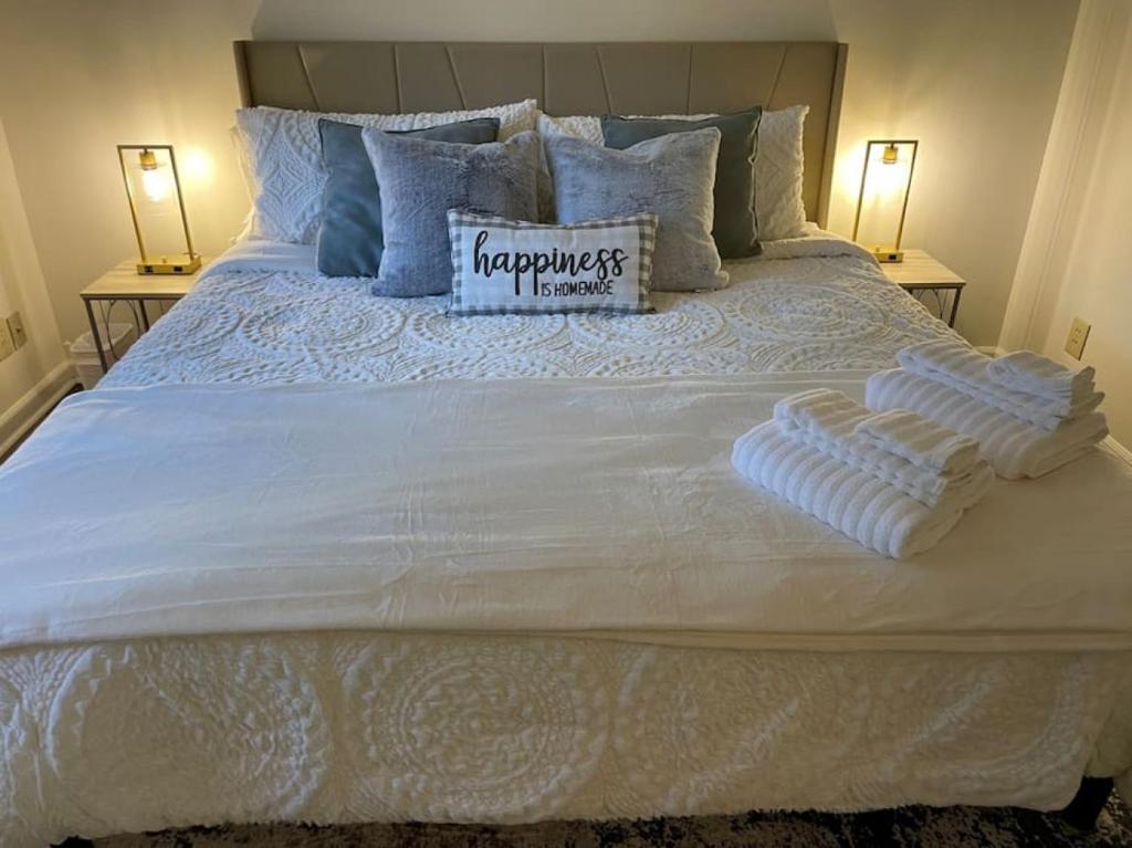 a white bed with two pillows and a sign on it at NEW King Beds, 86 inch RokuTV, and Massage at the Comfort Haven in Commerce