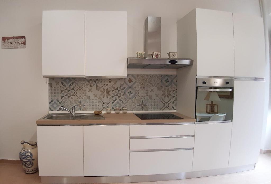 a white kitchen with a sink and a refrigerator at Civico in Gubbio