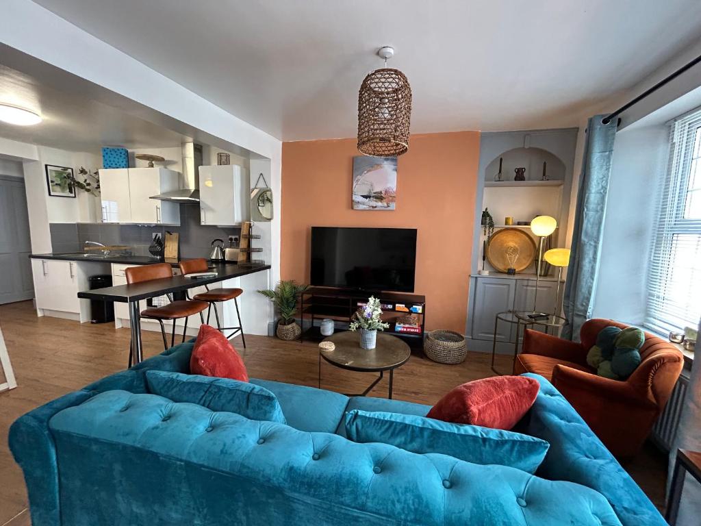 a living room with two blue couches and a kitchen at Fully Equipped Devon 2BR Cottage in Teignmouth