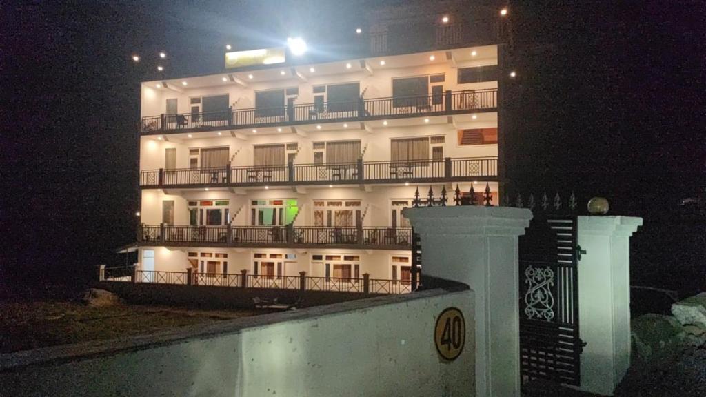 - un grand bâtiment blanc avec balcon la nuit dans l'établissement Hotel Sunshine Dharamshala, à Dharamshala
