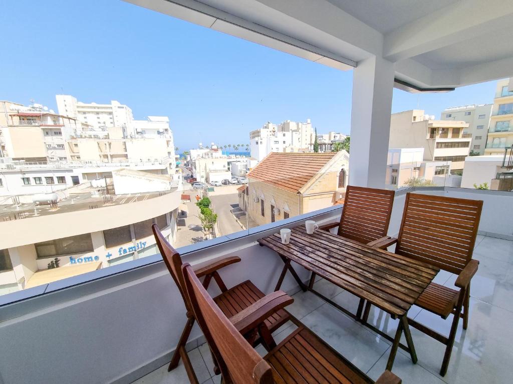 einen Balkon mit 2 Stühlen und einem Holztisch in der Unterkunft Sea Bay Apartment in Larnaka