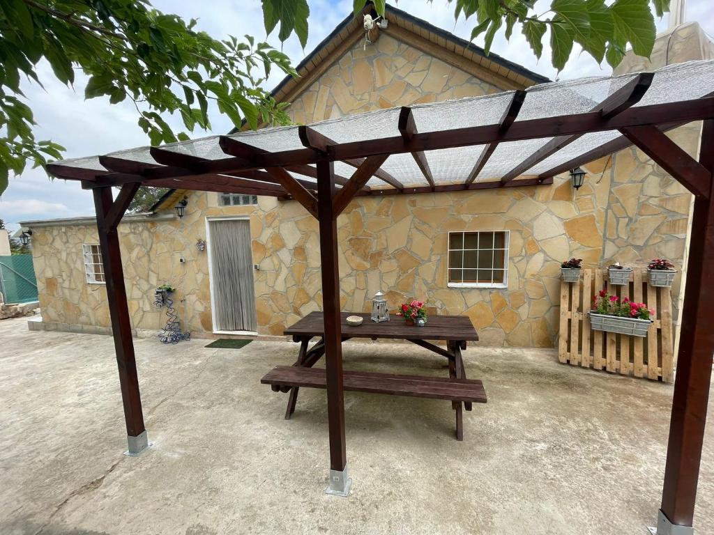 una mesa de picnic de madera frente a un edificio de piedra en Casita rural con piscina, en La Torre de Claramunt