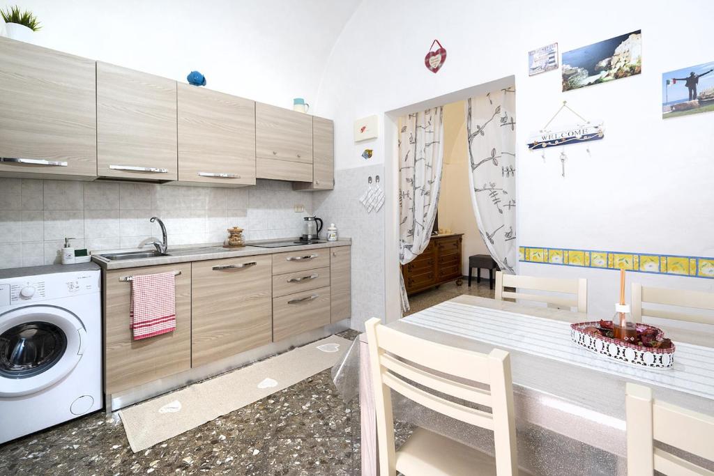 uma cozinha com uma máquina de lavar roupa e uma mesa com cadeiras em Chiarina rooms em Polignano a Mare
