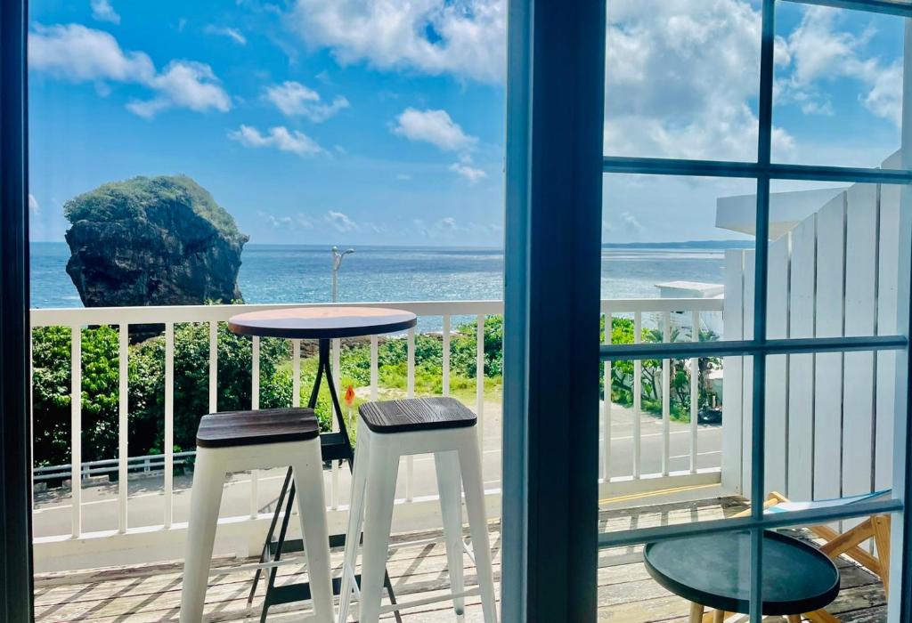 a balcony with a table and two stools at Canaan B&amp;B Kenting in Eluan