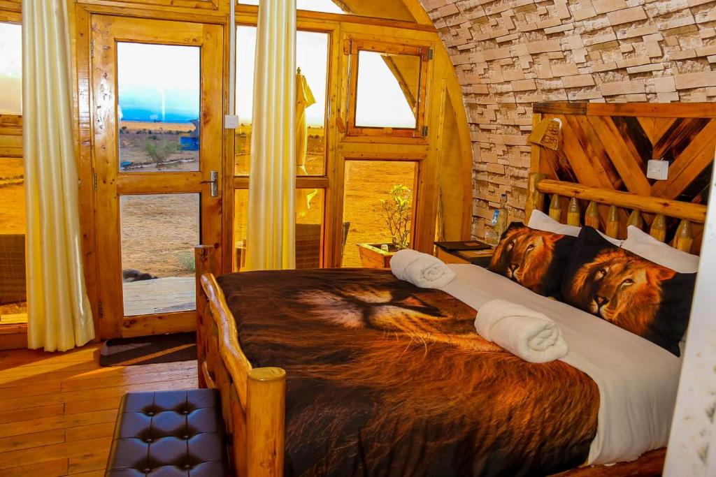 Un dormitorio con una gran cama de madera con una gran manta para perros. en Little Amanya Camp, en Amboseli