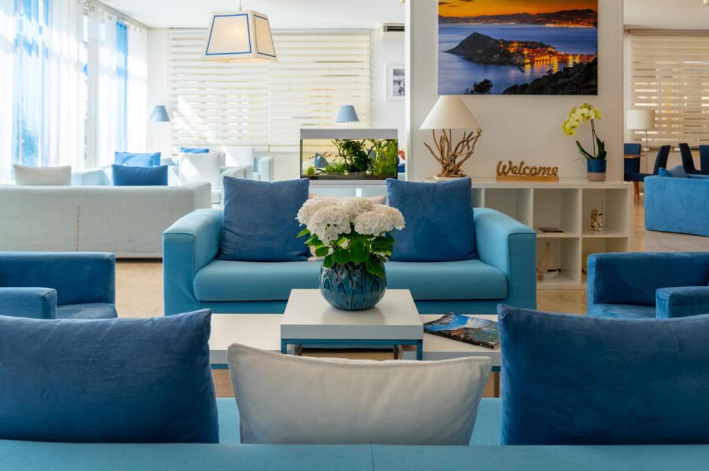 a lobby with blue couches and a table with flowers at Hotel Doria in Cavi di Lavagna