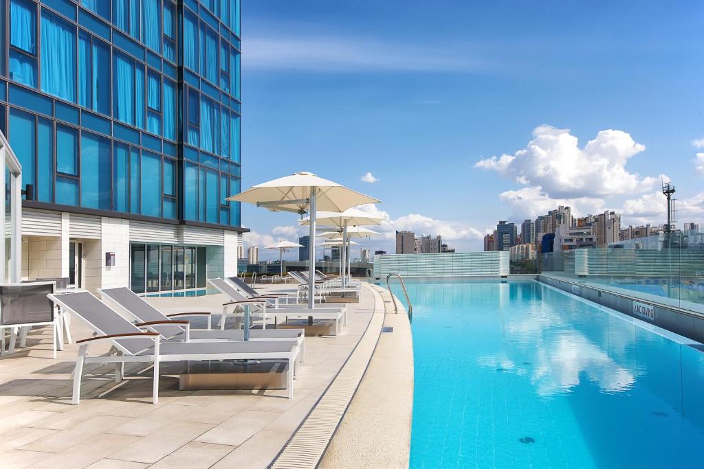 uma piscina com cadeiras e um guarda-sol num edifício em Orakai Songdo Park Hotel em Incheon