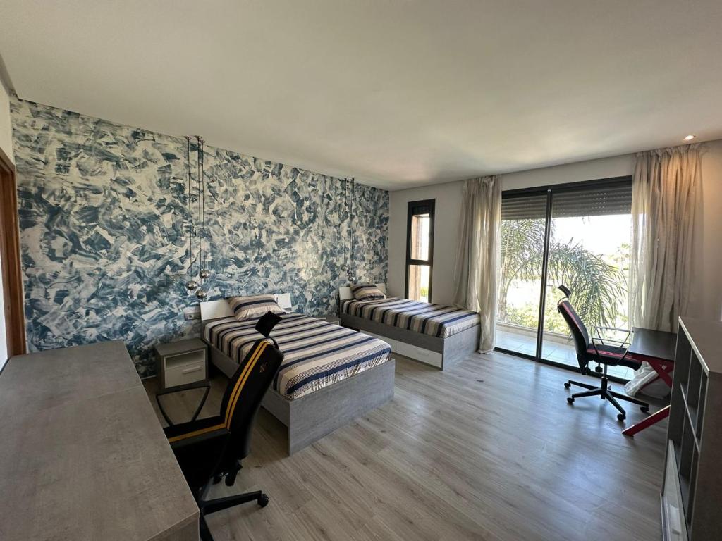1 Schlafzimmer mit 2 Betten, einem Tisch und einem Schreibtisch in der Unterkunft VILLA GOLF ARGAN in Marrakesch