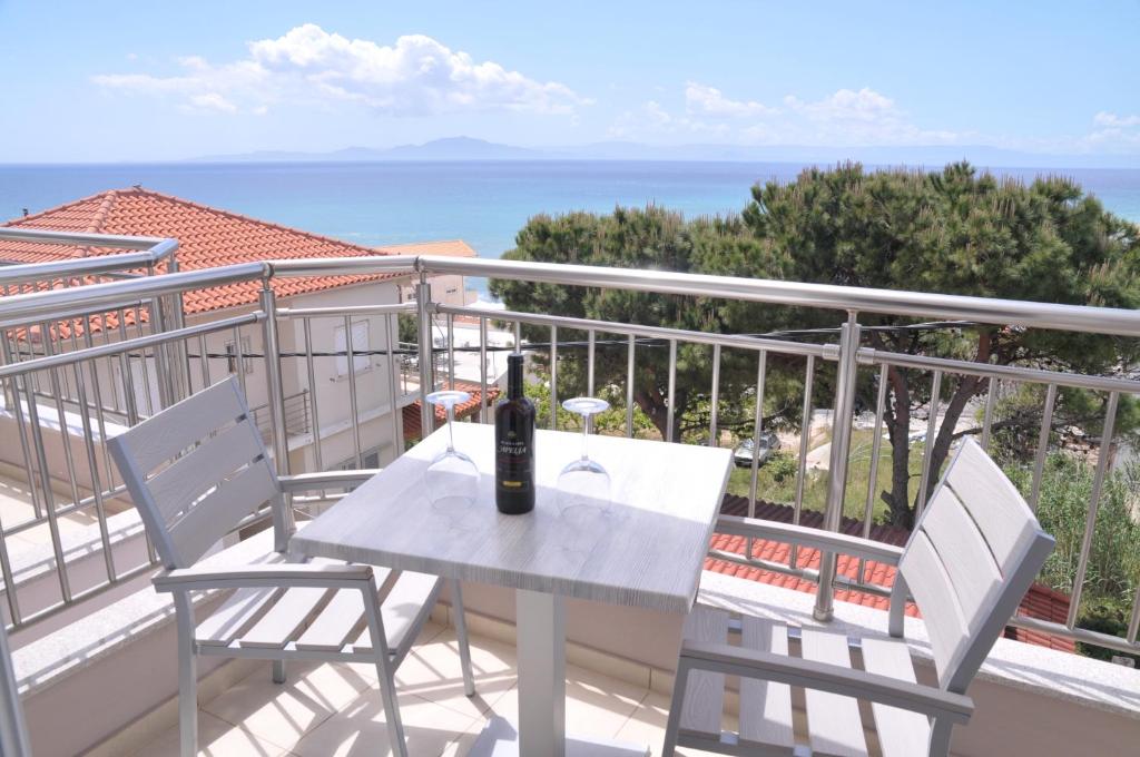 einen weißen Tisch und Stühle auf einem Balkon mit einer Flasche Wein in der Unterkunft Apartments Stoudios Georgias in Arkoudi