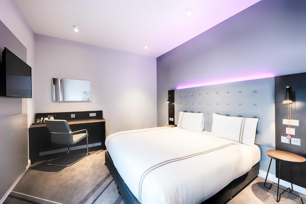 a hotel room with a large bed and a chair at Premier Inn Regensburg City Centre in Regensburg