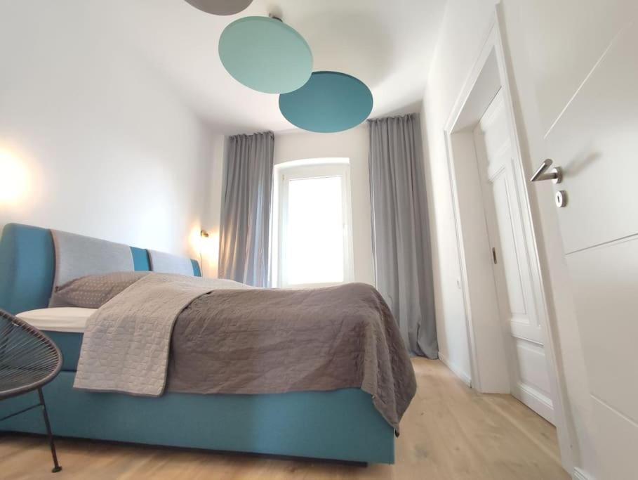 Un dormitorio con una cama azul y una ventana en 'BRIGHT 29' schöne, ruhige Innenstadtlage in Bielefeld, 400 m bis Klinikum Mitte, Smart TV, WLAN, en Bielefeld