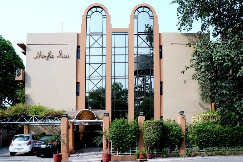 a building with large windows and a parking lot at Herfa INN Hotel Lahore in Lahore