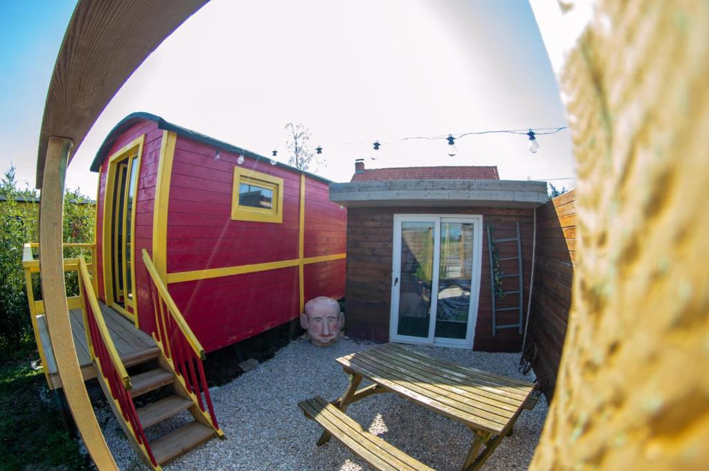einem roten Zughaus mit einer Bank und einem Stuhl in der Unterkunft Roulotte et sauna de Tonton Bouvy au domaine du Reuze in Winnezeele
