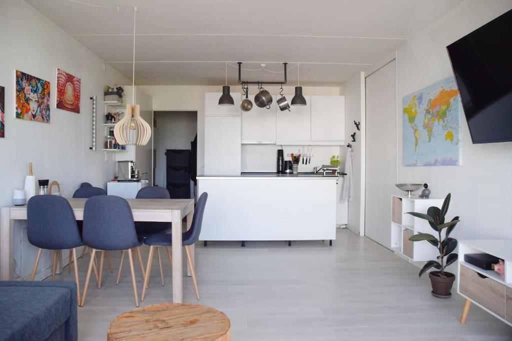a kitchen and dining room with a table and blue chairs at Nordic design flat including bikes in Copenhagen