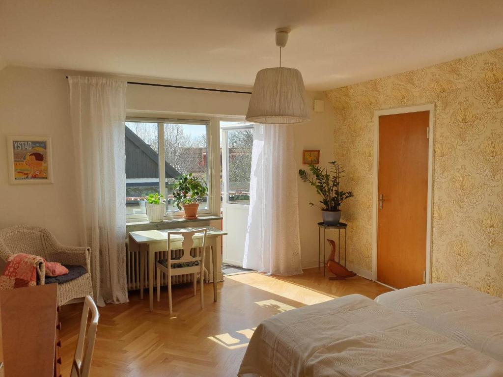 - une chambre avec un lit, une table et une fenêtre dans l'établissement Egen ovanvåning i charmig villa nära havet, à Ystad