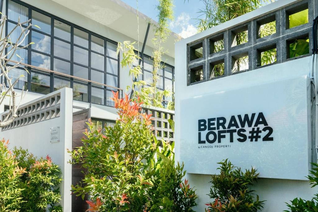 a sign on the side of a building with trees at Berawa Lofts #2 Canggu in Canggu