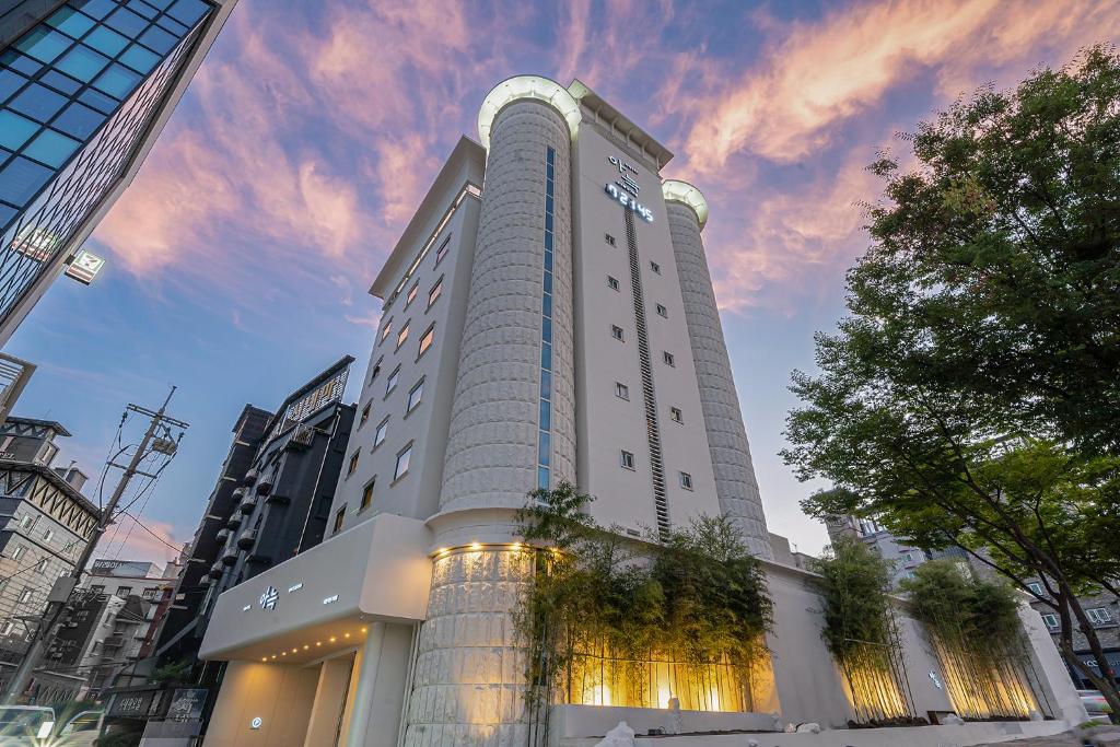 a tall white building with plants in front of it at The Hyoosik Aank Hotel Daejeon Yongjeon 2nd Branch in Daejeon