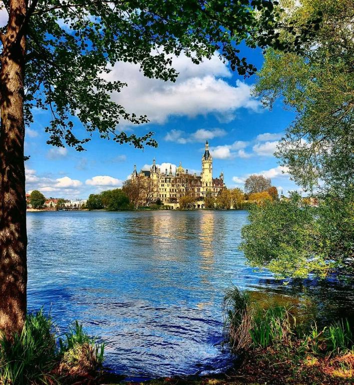 a view of a castle on a lake with a building at Modernes Wohnen am See in Schwerin