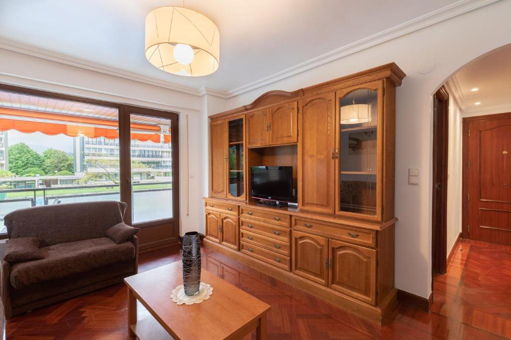 una sala de estar con un gran centro de entretenimiento de madera con TV en Euromar - baskeyrentals, en Zarautz