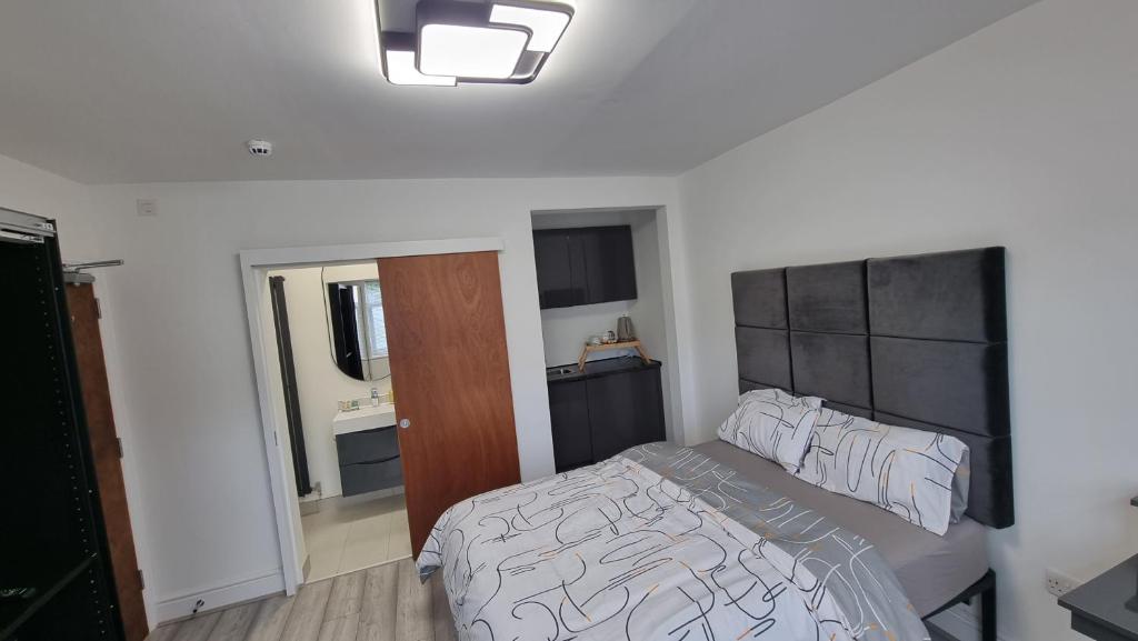 a bedroom with a bed with a black and white comforter at Stylish Suites with kitchenette in London Colney
