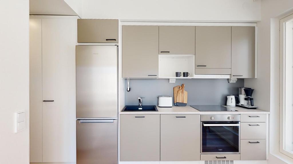 une cuisine avec des armoires blanches et des appareils en acier inoxydable dans l'établissement Kotimaailma Apartments Loimu VIII, à Oulu