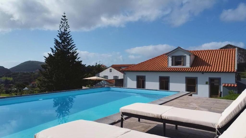 a swimming pool with two chairs and a house at Azores Haven Hill in Horta