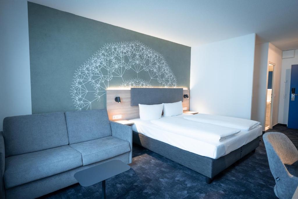 ein Schlafzimmer mit einem Bett und einem Sofa in der Unterkunft Taste Hotel Jettingen in Jettingen-Scheppach