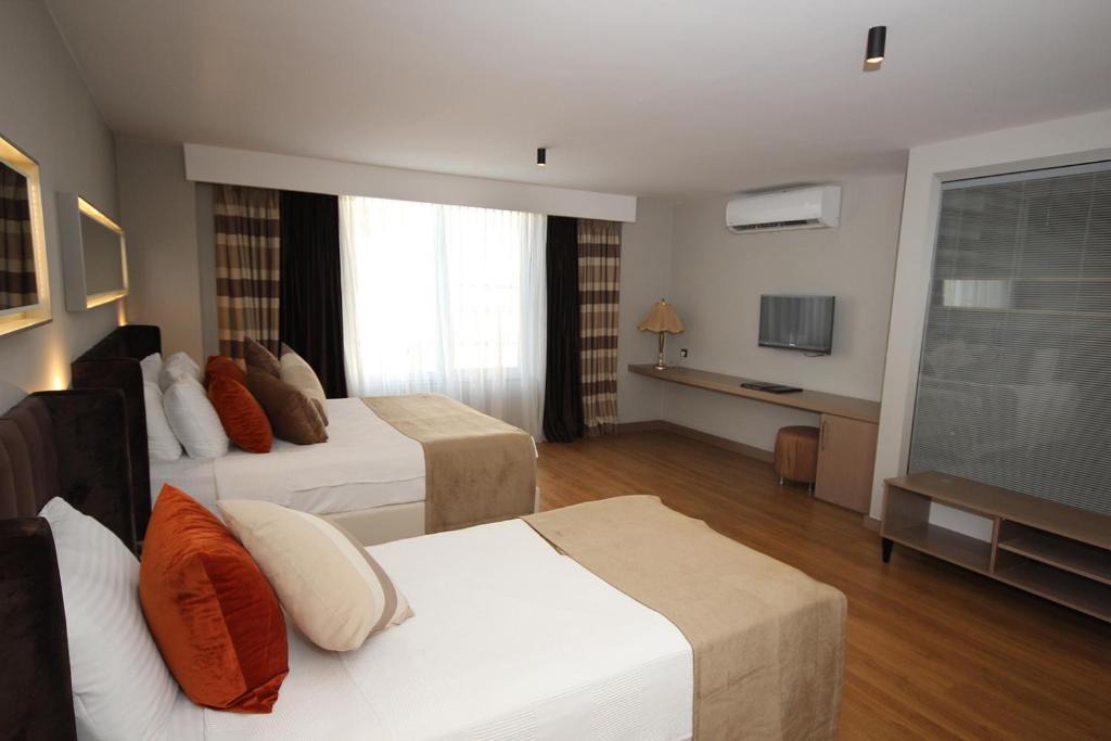 a hotel room with two beds and a flat screen tv at Nobel Hotel in Mersin