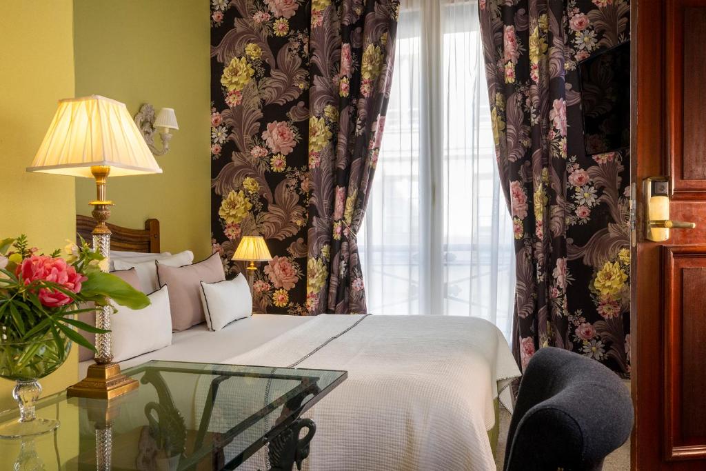 a bedroom with a bed and a window with curtains at Hôtel Des Marronniers in Paris