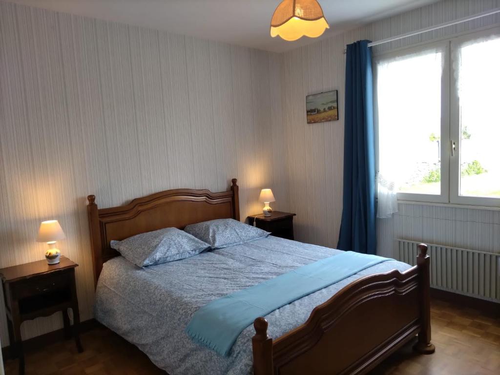Schlafzimmer mit einem Bett mit blauer Bettwäsche und einem Fenster in der Unterkunft Trouz Ar Mor in Penmarcʼh