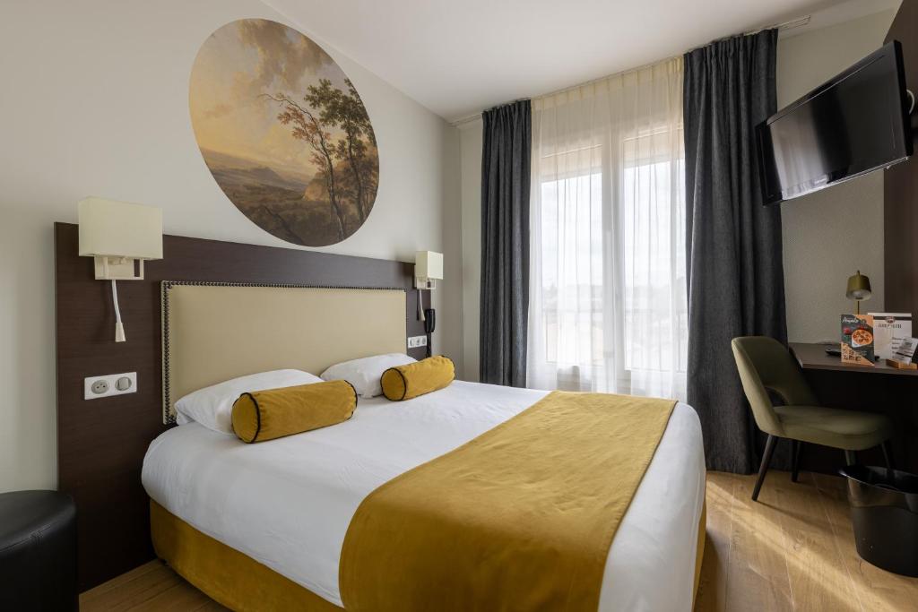 a hotel room with a large bed and a desk at Brit Hotel Europ Bergerac in Bergerac