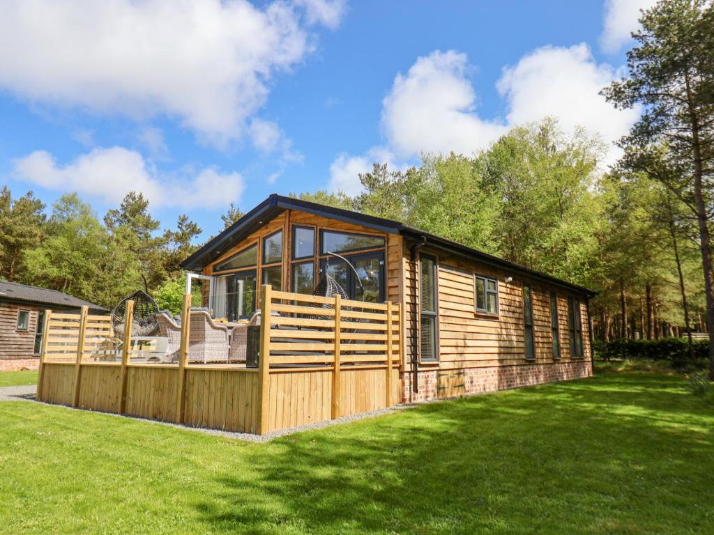 a large wooden cabin in a grassy yard at Ewe Crag Beck Lodge in Whitby