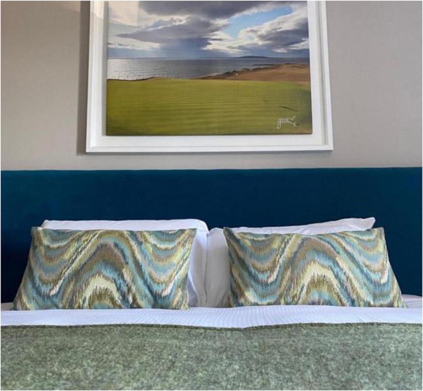 uma cama com duas almofadas e um quadro na parede em The Marine Boutique Hotel em Ballybunion