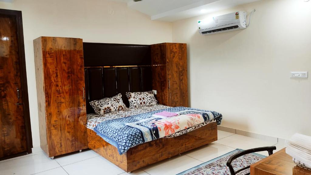 a bedroom with a bed with a wooden headboard at THE RAJMANI MOTEL -- LUXURY STUDIO ROOMS -- LPU Law Gate in Phagwāra