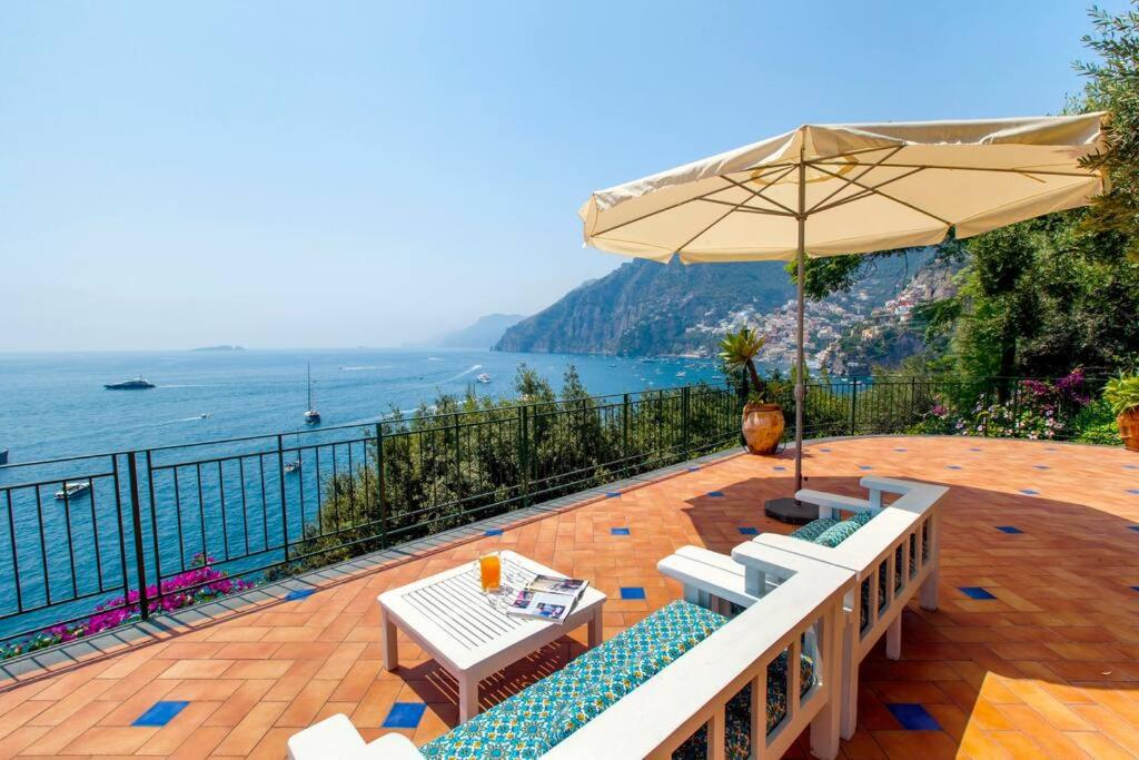 a patio with a table and chairs and an umbrella at La Villa Positano - Luxury villa with private sea access in Positano