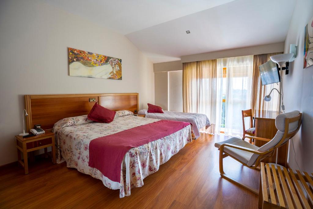 ein Hotelzimmer mit 2 Betten und einem Stuhl in der Unterkunft Hotel Los Barruecos in Malpartida de Cáceres