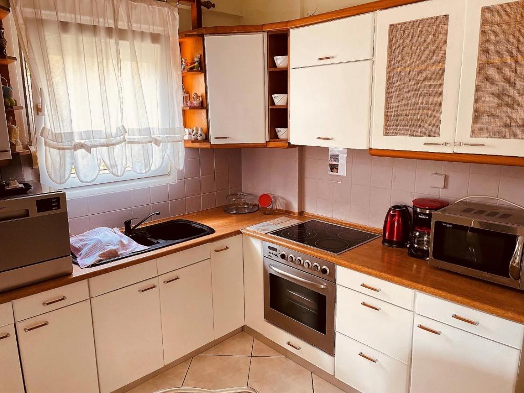 kuchnia z białymi szafkami i kuchenką w obiekcie Pavlina w mieście Kallithea